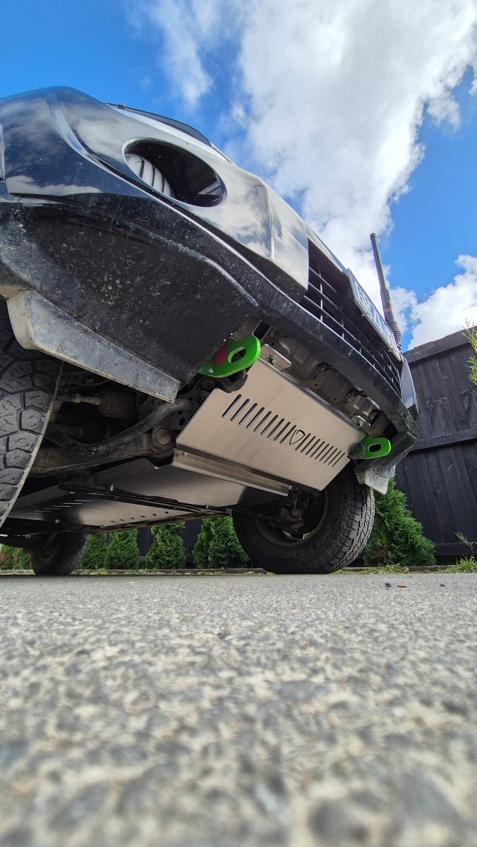 Underbody view of a vehicle showing the front bash plates installed on the frame.